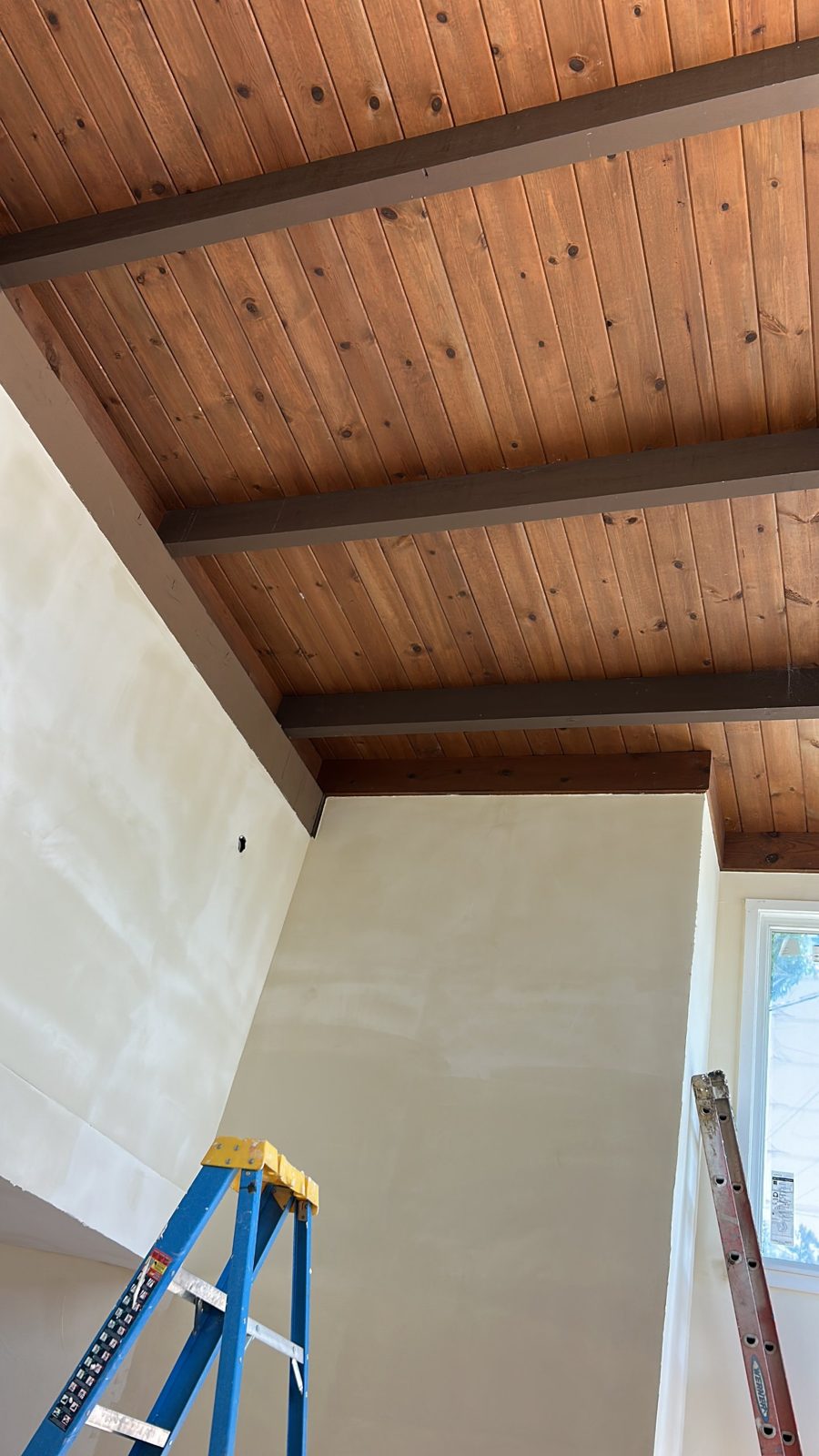 Vaulted walls skimmed and primed under a wood ceiling